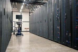 An aisle in a data centre - with rows of cages containing servers on either side. There is a data centre 'crash cart' at the far end of the aisle.